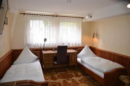 Zimmer mit 2 Betten, einem Schreibtisch und einem Fenster in der Unterkunft Hotel Waldersee in Hannover