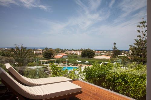 eine Terrasse mit 2 Liegestühlen und einem Pool in der Unterkunft Artemis Village Apartments & Studios in Stavros
