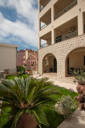 a building with a palm tree in front of it at Guest House Medin in Petrovac na Moru