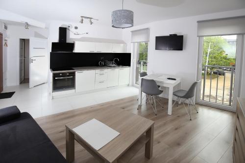 a kitchen and living room with a table and chairs at 100-SIO Apartamenty in Koszalin