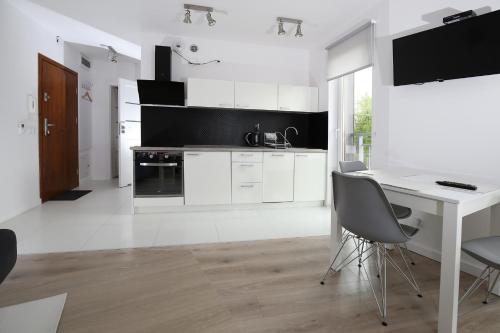 a white kitchen with a desk and a table at 100-SIO Apartamenty in Koszalin