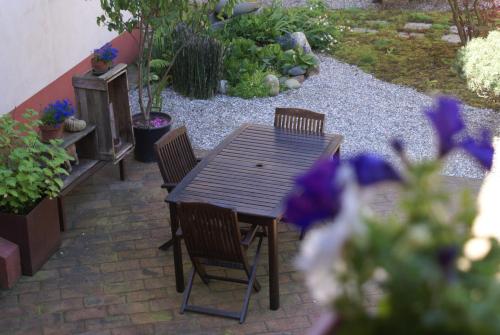 a wooden table and chairs on a patio with flowers at Studio Sforzesco in Bellinzago Novarese