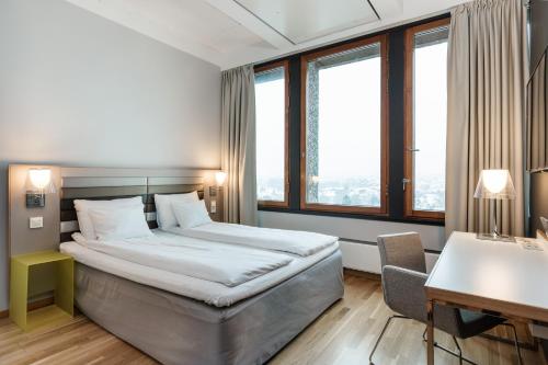 um quarto de hotel com uma cama, uma secretária e janelas em Quality Hotel 33 em Oslo