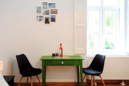 Stylish Apartman Szeged في سيجد: طاولة خضراء مع زجاجة من النبيذ وكرسيين