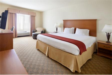 a hotel room with a large bed and a chair at Holiday Inn Express Hotel & Suites Zapata by IHG in Zapata