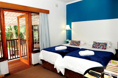 a bedroom with a bed with blue walls and a balcony at Oliveroom Self Catering and B&B in Durban