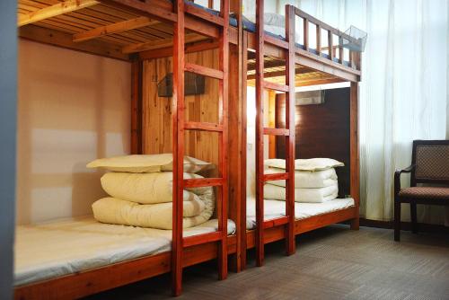 kilka łóżek piętrowych z poduszkami w pokoju w obiekcie Huangshan Tangkou Haoshi International Youth Hostel w mieście Huangshan
