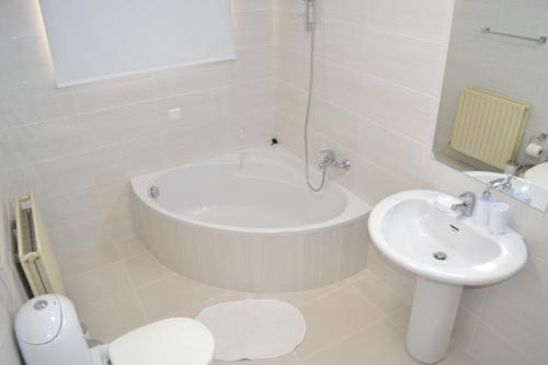 a white bathroom with a tub and a sink at Marianna Hotel Apartments in Limassol