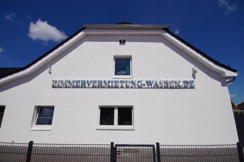 un bâtiment blanc avec un panneau sur son côté dans l'établissement Pension / Zimmervermietung Wasbek, à Wasbek