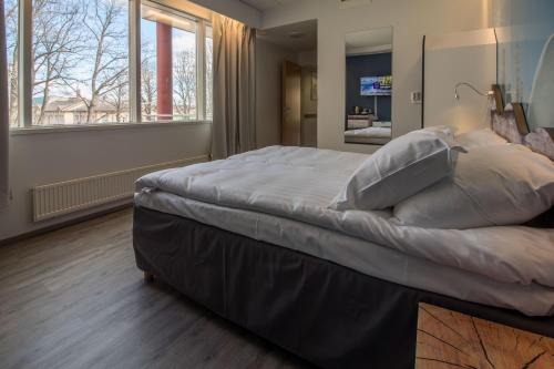 a bedroom with a large bed in a room with windows at Hotelli Uninen Loviisa in Lovisa