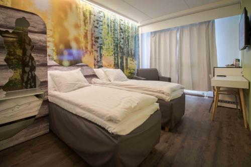 a hotel room with two beds and a desk at Hotelli Uninen Loviisa in Lovisa