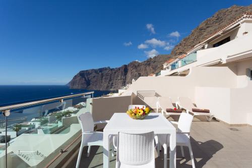 a white table and chairs on a balcony overlooking the ocean at Royal Sun Resort in Acantilado de los Gigantes