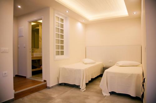 two beds in a room with white walls at Artemis Village Apartments & Studios in Stavros