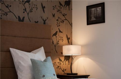 a bedroom with a bed with a lamp and a wall at Boutique-Hotel Garni Bellevue Davos Wiesen in Wiesen