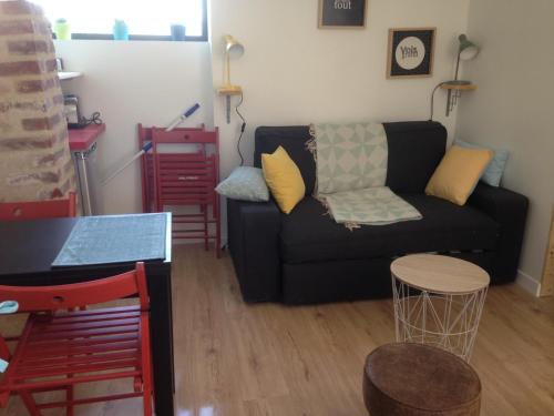un salon avec un canapé noir et une table dans l'établissement La sucrette, à Amboise