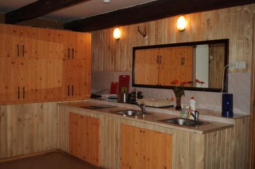 a kitchen with two sinks and a mirror and wooden cabinets at Guest House Ventas Rumba in Kuldīga