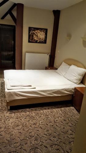 a bedroom with a large bed with white sheets at Kompleks Fontana in Vladičin Han