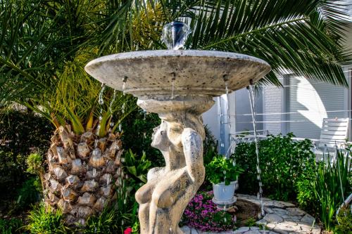 a stone fountain in a garden with a palm tree at Villa Fontana in Starigrad-Paklenica