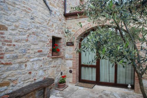 a stone building with a door and a tree at Agriturismo Scannano in Serre di Rapolano