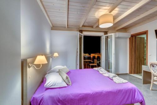 a bedroom with a purple bed with a balcony at Ethrion in Ermoupoli