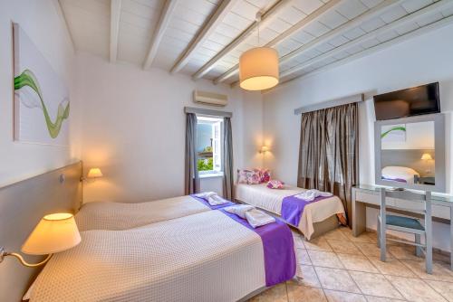 a bedroom with two beds and a desk and a window at Ethrion in Ermoupoli