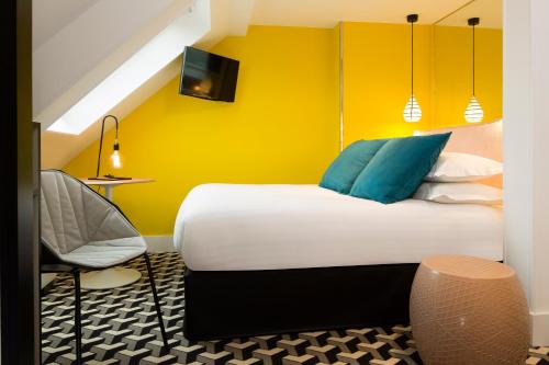 a bedroom with a bed and a yellow wall at Hotel Haussmann Saint Augustin in Paris