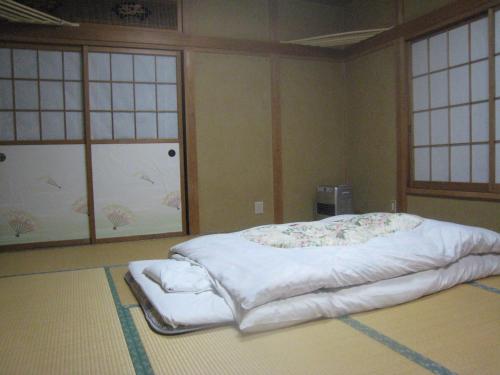 Cama grande en habitación con 2 ventanas en Nitaya en Minakami