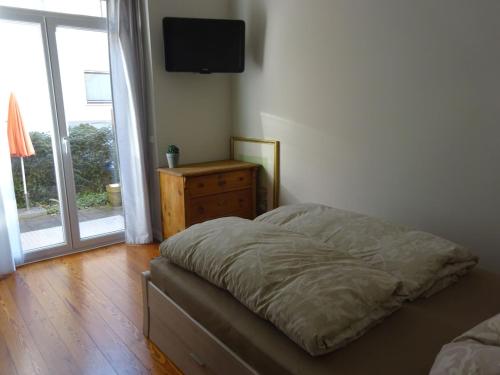 ein Schlafzimmer mit einem Bett, einer Kommode und einem TV in der Unterkunft City Appartement in Baden-Baden