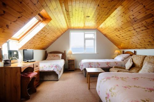 a attic room with two beds and a tv at Seabreeze Apartment in Renvyle