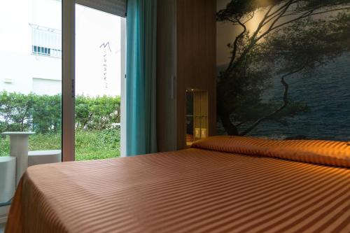 a bedroom with a bed and a large window at Hotel Miramare in Pineto