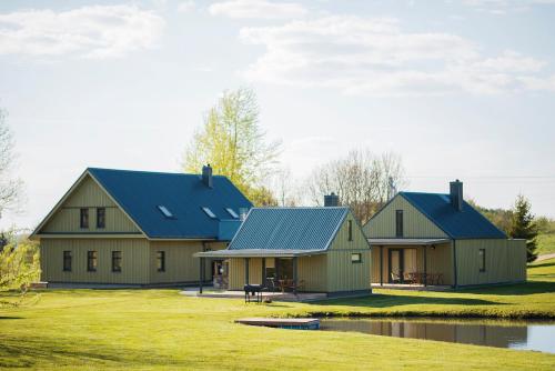 duas casas com telhados azuis ao lado de um lago em Aitvaras em Anykščiai