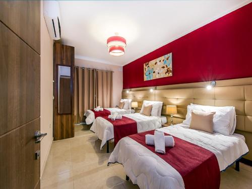 two beds in a hotel room with red walls at Bayside Apartments in St Julian's
