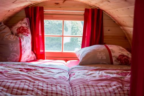 Cama en habitación con ventana y cortinas rojas en Camping-Erbenwald, en Neubulach