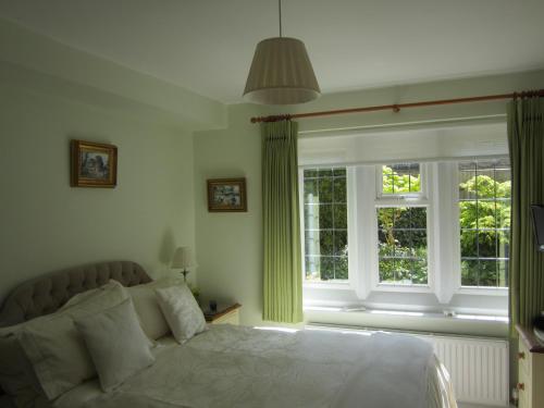 a bedroom with a bed and two windows at Coombe House in Bourton on the Water