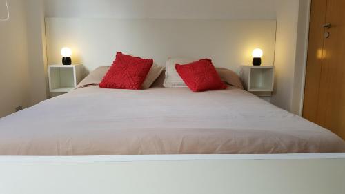 a white bed with two red pillows on it at Loft Almagro in Buenos Aires