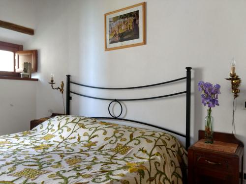 a bedroom with a bed and a vase of purple flowers at Podere Pancoli in Massa Marittima