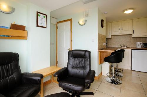 a living room with two chairs and a table and a kitchen at Seabreeze Junior Suite Renvyle in Renvyle