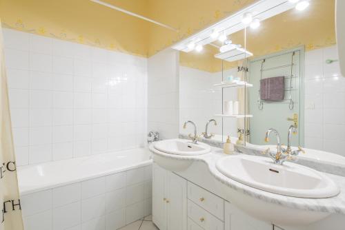 a bathroom with two sinks and a tub and a mirror at Chateau de Breuil en Beaujolais in Salles-Arbuissonnas