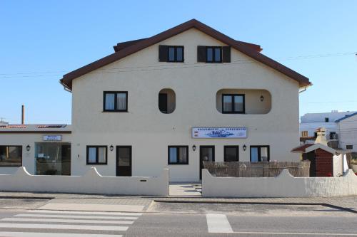 a white building with black windows on a street at Baleal à Vista in Baleal
