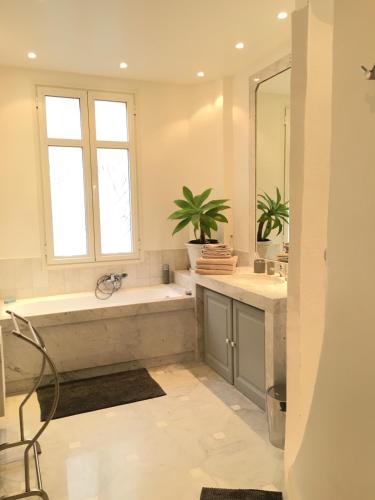 une salle de bain avec une baignoire, un lavabo et un miroir dans l'établissement Palais Haydee, à Nice