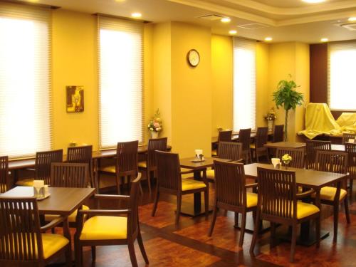 a restaurant with tables and chairs and a clock on the wall at Hotel Route-Inn Suwa-Inter2 in Suwa