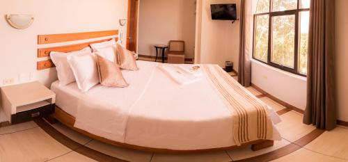 a bedroom with a large bed with white sheets and pillows at Sumaj Casa Hotel in Tarapoto