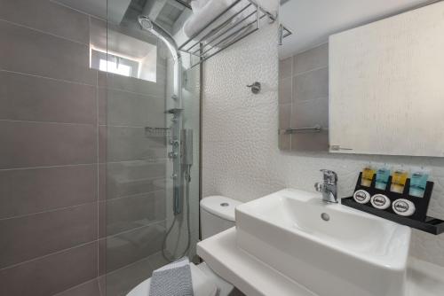 a white bathroom with a sink and a shower at Lindos Citrin Studios in Líndos