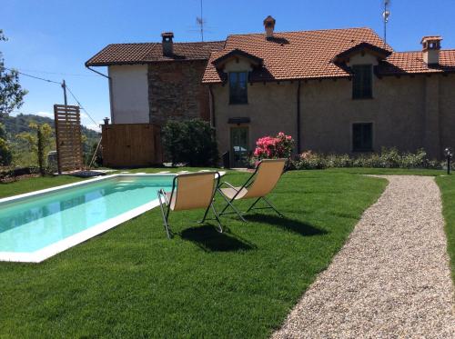 two chairs sitting in the grass near a swimming pool at Il Bosso del Lago in Ameno