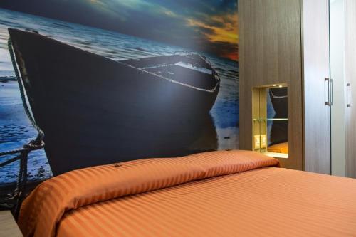 a bedroom with a painting of a boat on the wall at Hotel Miramare in Pineto