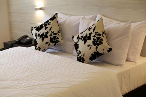 a bed with black and white pillows and a phone at Alba Uno Hotel in Cebu City