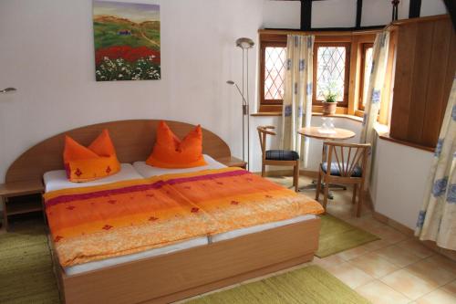 a bedroom with a bed with orange pillows and a table at Bella Citta Vecchia in Limburg an der Lahn