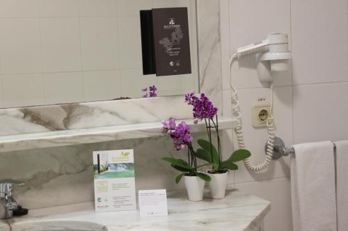 a bathroom with a sink with purple flowers on a counter at Hotel Suave Mar in Esposende