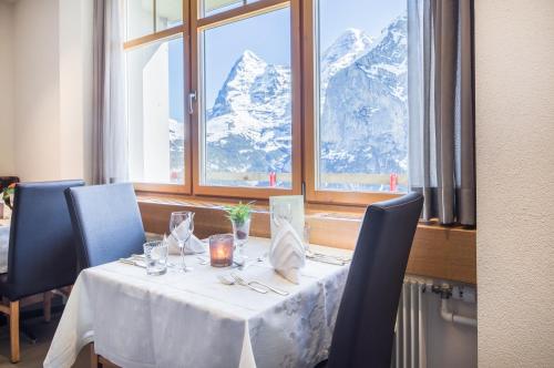 a table in a restaurant with mountains in the window at Hotel Edelweiss Superior in Mürren