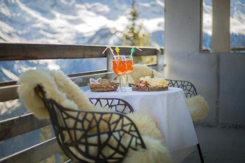 einen Tisch mit einem Getränk und Speisen auf dem Balkon in der Unterkunft Hotel Edelweiss Superior in Mürren